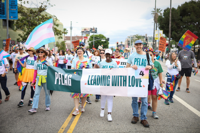 A group of PFLAG members holding a banner at a Pride parade.